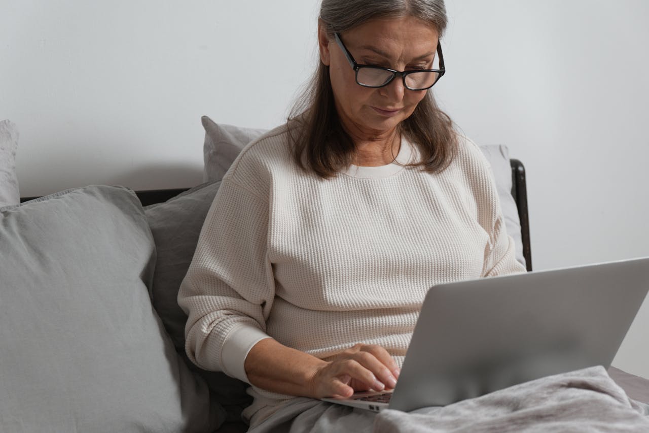 A Woman in White Sweater Sitting while Using a Laptop